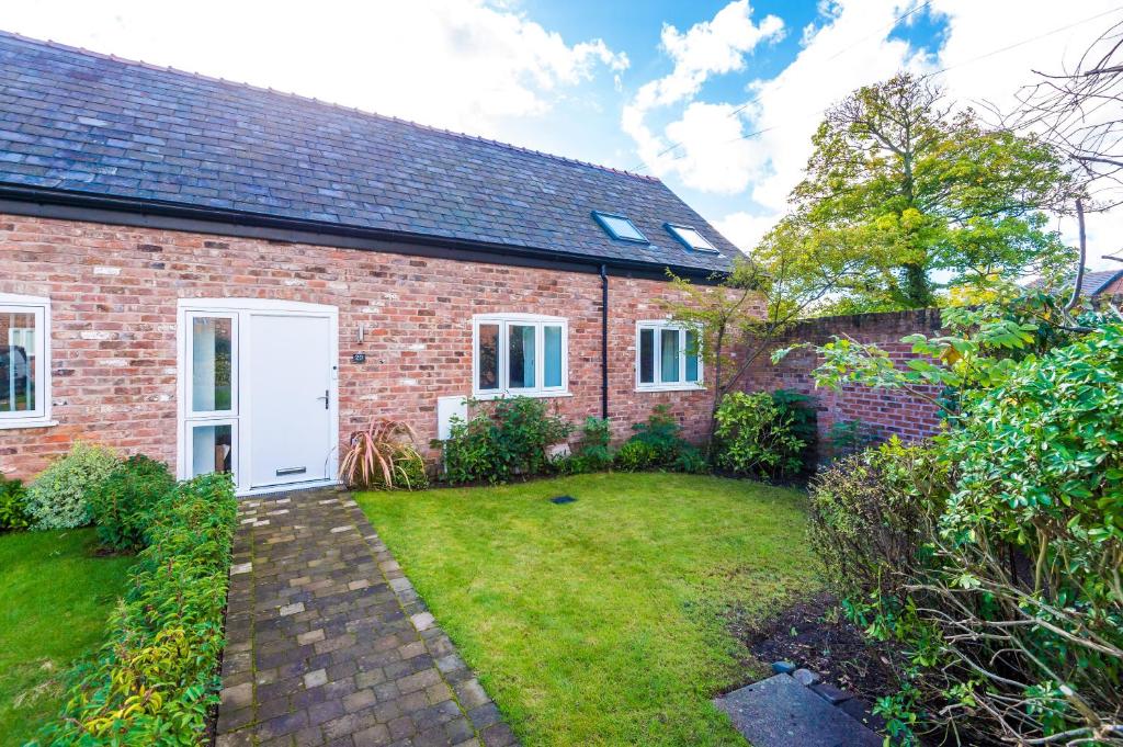 uma casa de tijolos com uma porta branca e um quintal em Wild Drive Chester - Stunning cottage in CH1 with Double Parking em Chester