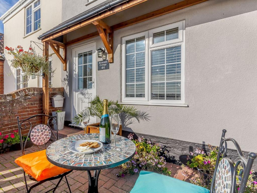 a table with a bottle of wine on a patio at Riverside Cottage in Reedham