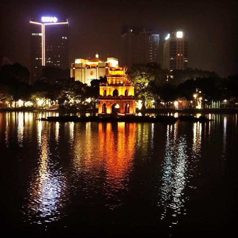 a lit up building in the middle of the water at night at Best Price Hồ Gươm Apartments for Long Stay in Hanoi