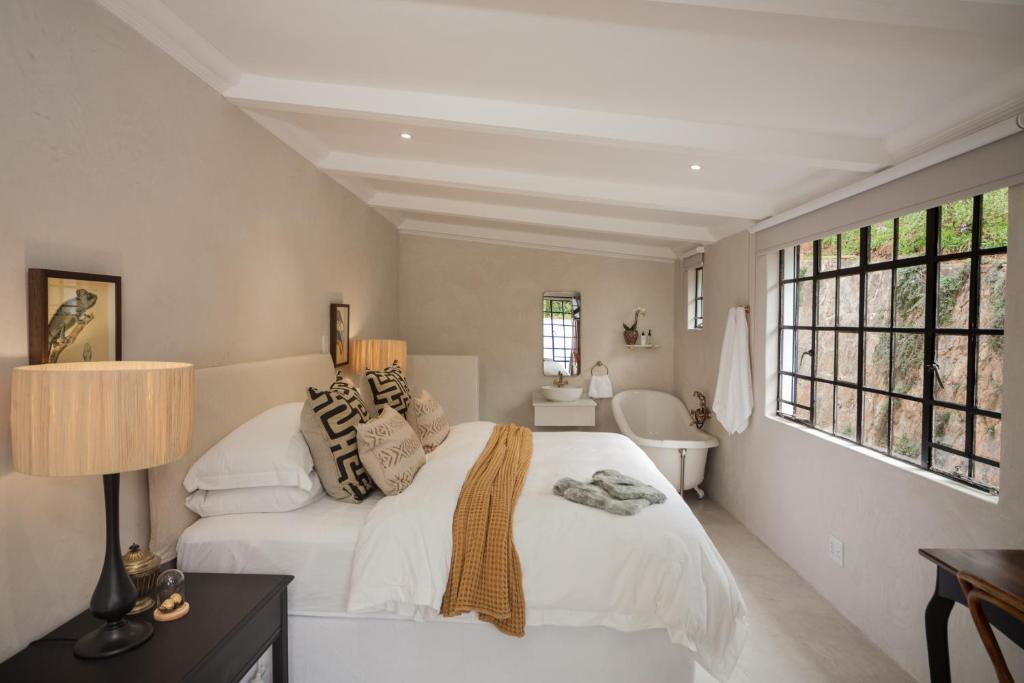 a white bedroom with a bed and a window at Viewpoint Estate Guest House in Haenertsburg