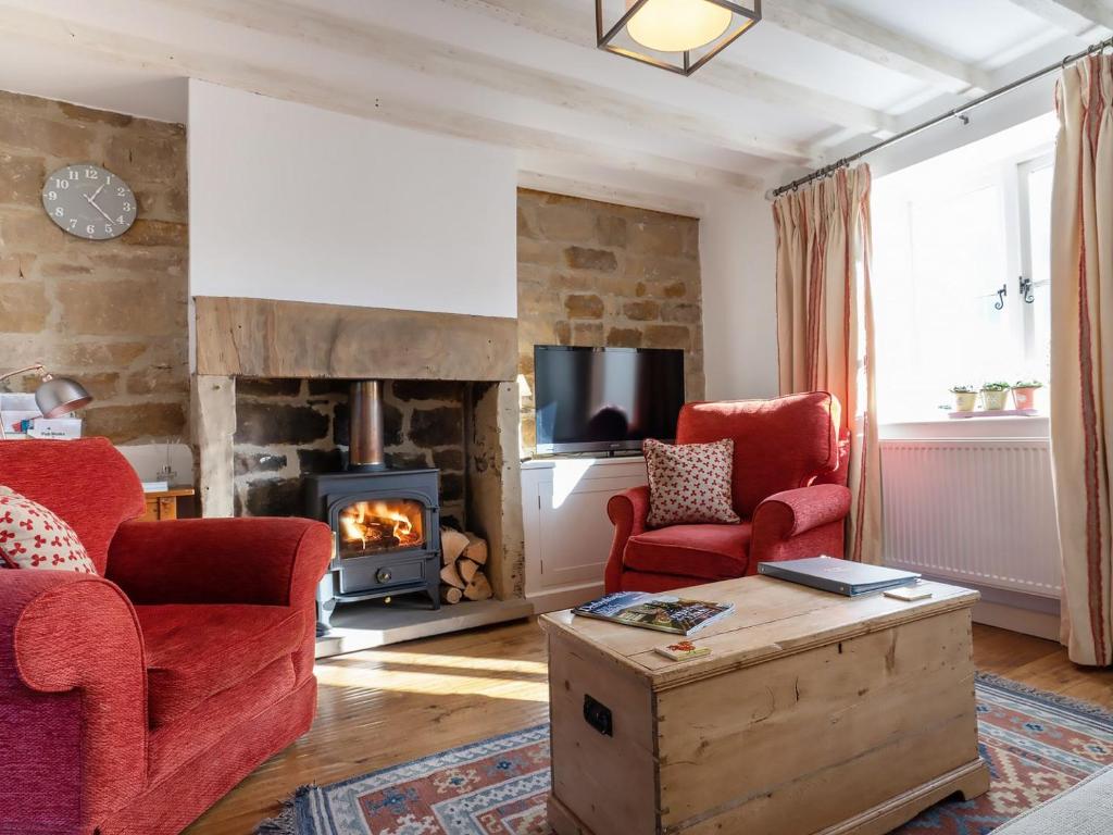 a living room with two chairs and a fireplace at Periwinkle Cottage in Great Longstone