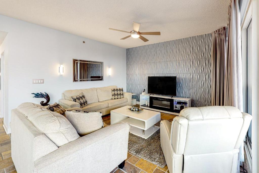 a living room with white furniture and a flat screen tv at TOPS'L Tides 0207 in Destin