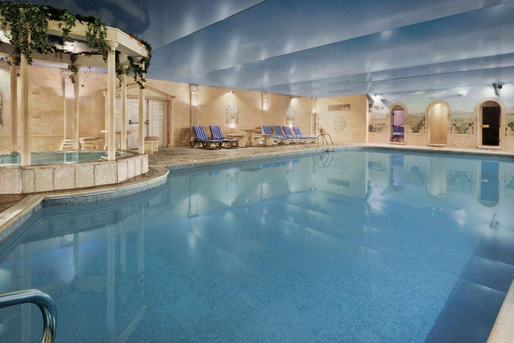 a large swimming pool with blue water in a building at Cwrt Bleddyn Hotel & Spa in Usk