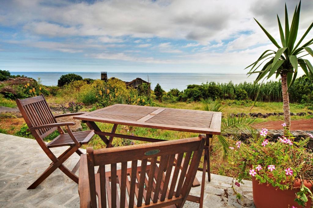 einen Holztisch, eine Bank, einen Tisch und eine Palme in der Unterkunft Casa Cachalote - Ferienhaus auf den Azoren in São Caetano