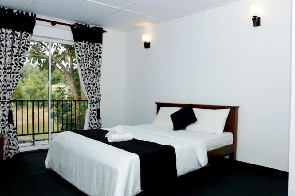 1 dormitorio con 2 camas y ventana en Sadhara River View Lodge, en Kandy