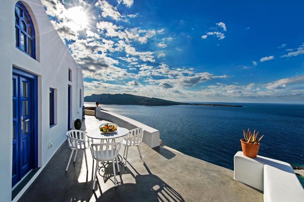 a balcony with a table and chairs overlooking the water at Domus Solis Luxury Villa in Oia