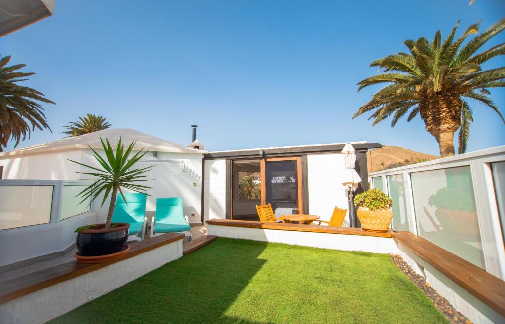 a patio with a lawn and chairs and a palm tree at The Luxury Penthouse at Casita Palmera in Haría