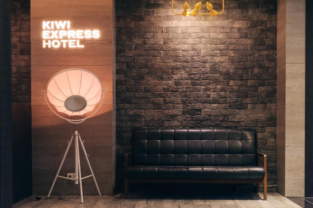 a black leather couch next to a brick wall at Kiwi Express Hotel-Taichung Station II in Taichung