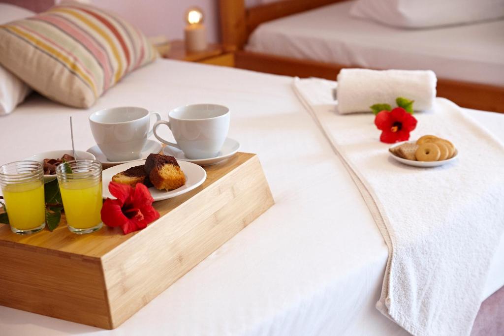ein Tablett mit Frühstückszutaten und Getränken auf einem Bett in der Unterkunft Elea Terra Hotel in Matala