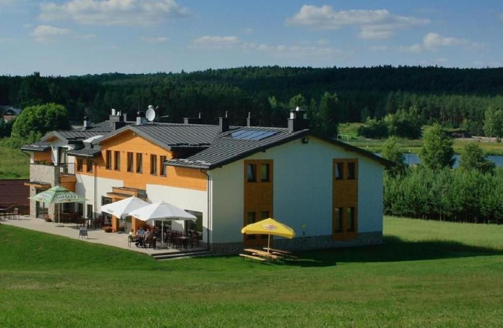 a large house with tables and umbrellas in a field at Ośrodek Wypoczynkowy Jacnia in Jacnia