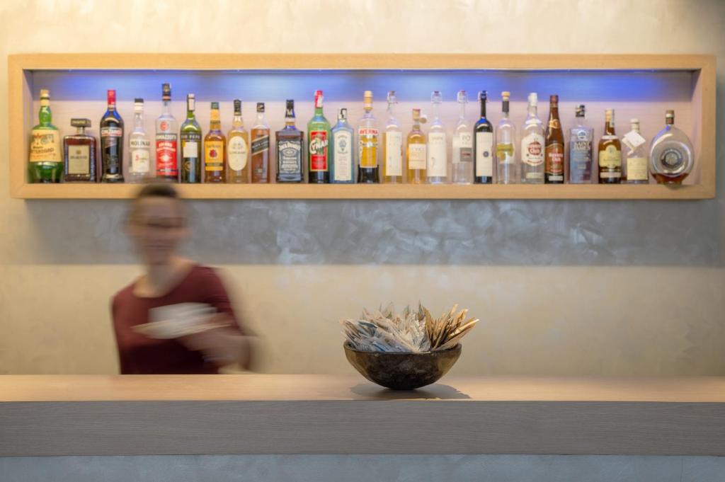 a woman standing behind a bar with bottles of alcohol at Methis Hotel & SPA in Padova