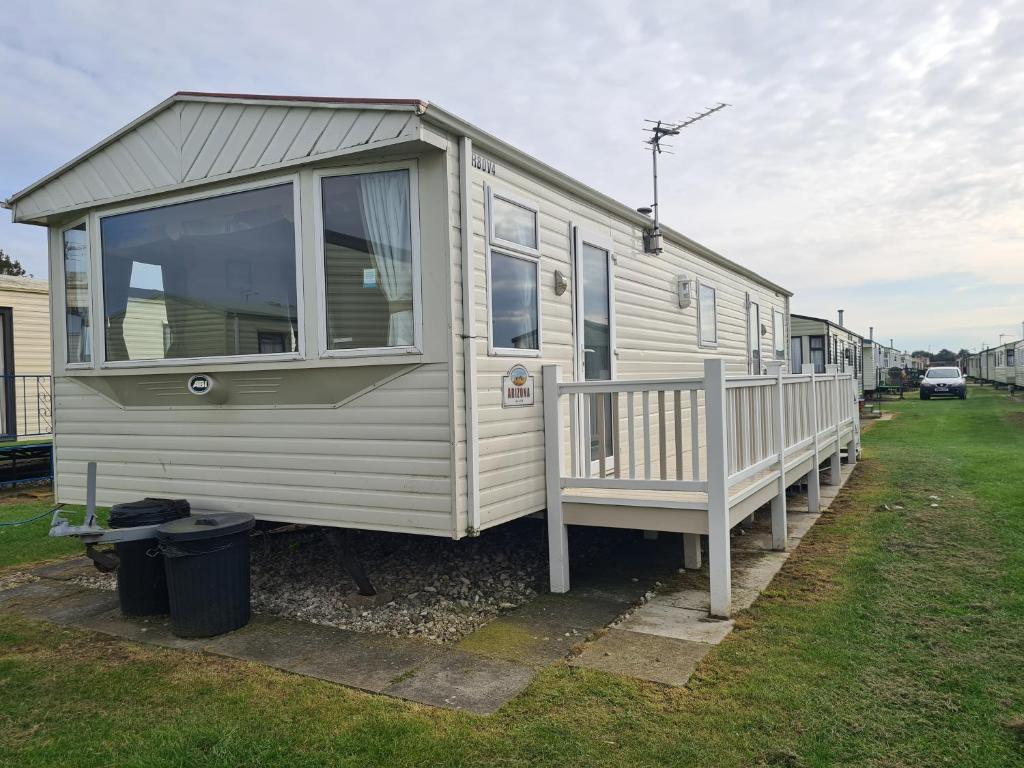 a white caravan with a porch and a fence at 8 berth central heated on Coral Beach ABI CB in Ingoldmells