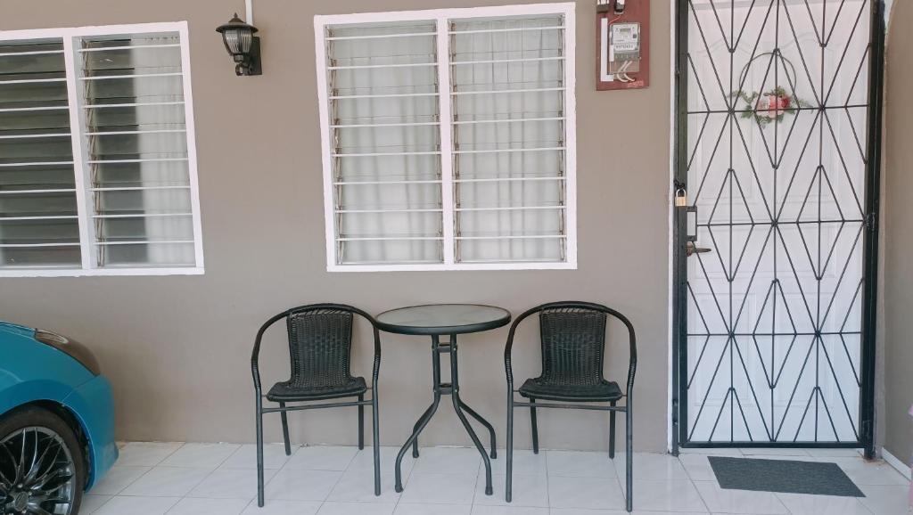 a table and two chairs in front of a door at De'Manda Homestay in Sandakan