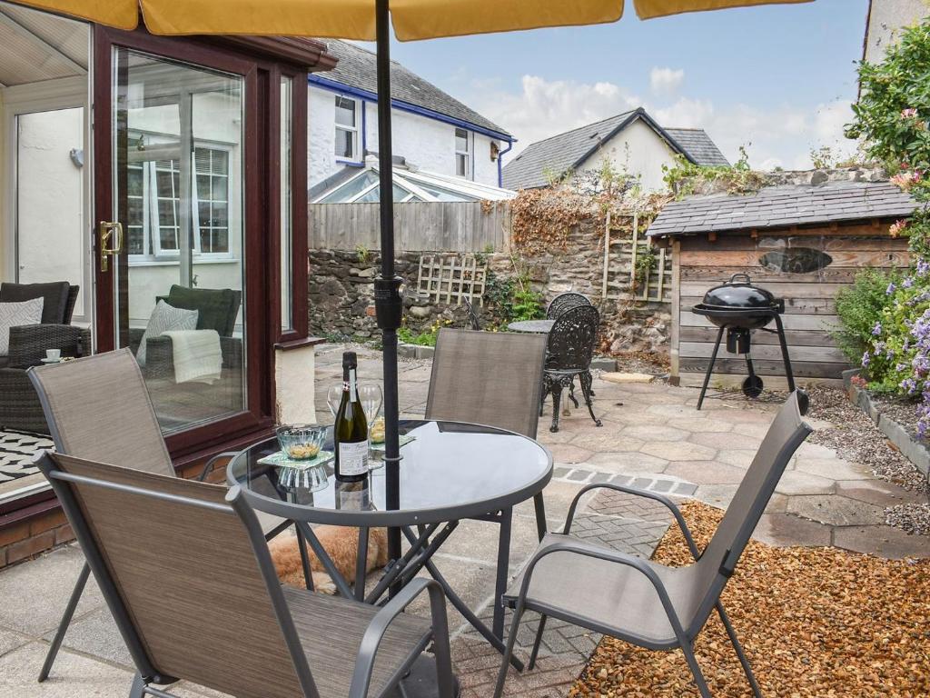 patio ze stołem, krzesłami i parasolem w obiekcie Old Road Cottage w mieście Conwy