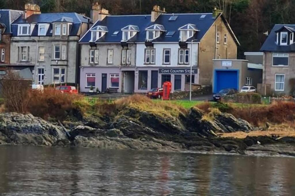 a group of houses next to a body of water at Superb Loch Side Apartment with Sea & Sunset Views in Helensburgh