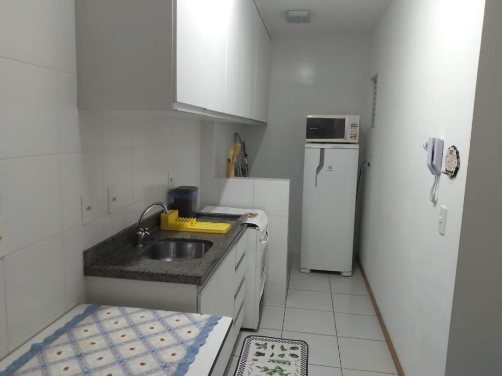 een kleine keuken met een wastafel en een koelkast bij Apartamento ao lado da Vila Germânica in Blumenau