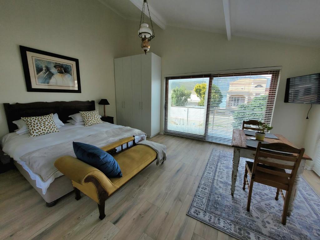 a bedroom with a bed and a table with a chair at Leehaven Apartment in Hout Bay