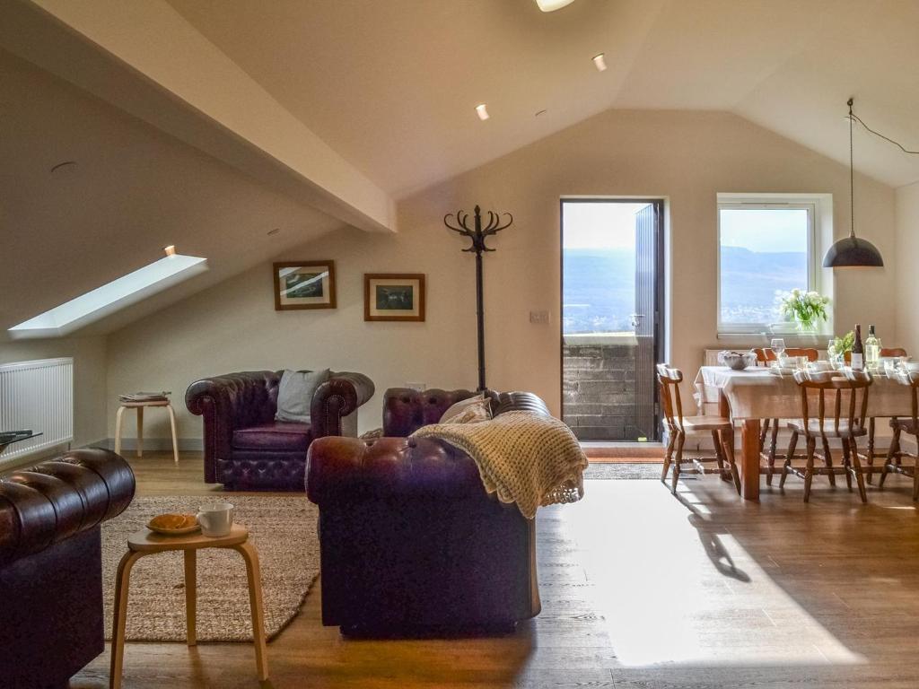 a living room with couches and a dining room with a table at The Barn Pencoed Farm in Aberdare