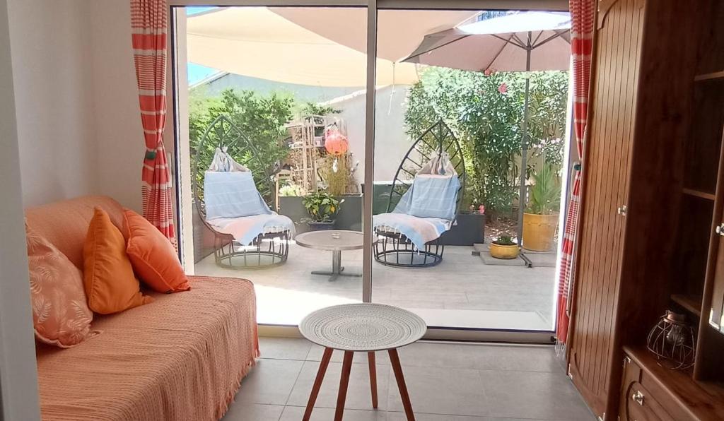 una camera con divano e patio con sedie e ombrellone di Escale à Bouzigues a Bouzigues