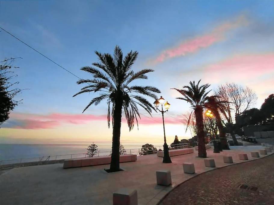 een rij palmbomen op een stoep bij de oceaan bij Casa Titen in Ventimiglia