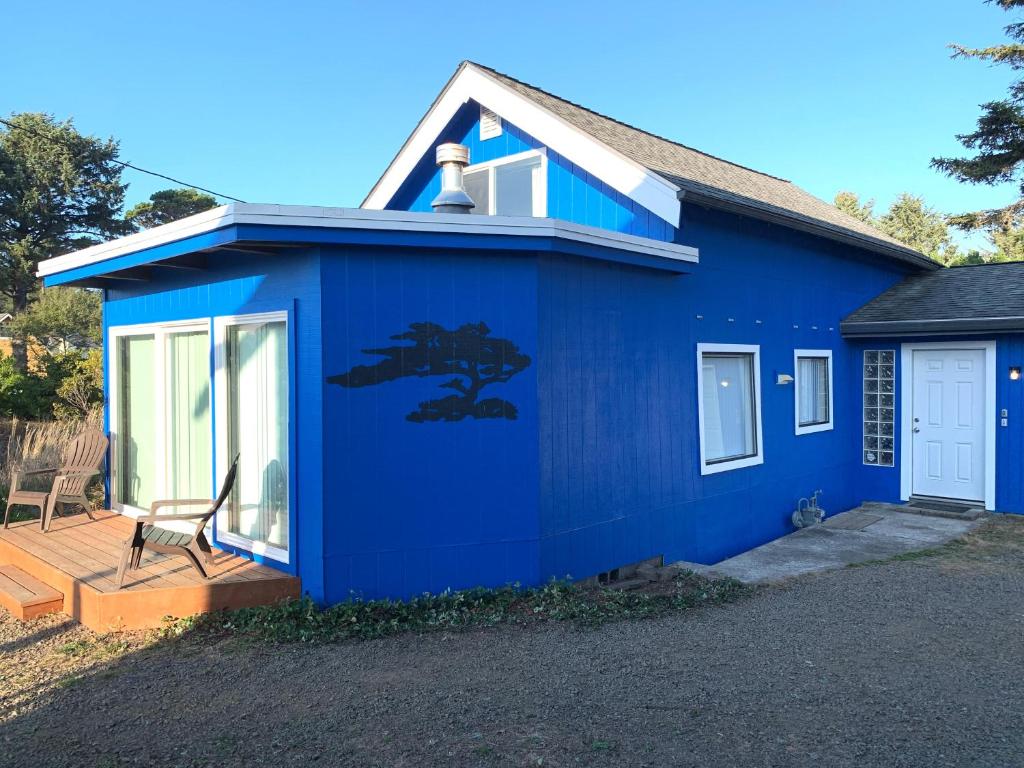 a blue house with a tree painted on the side at Woodley Beach House in Lincoln Beach