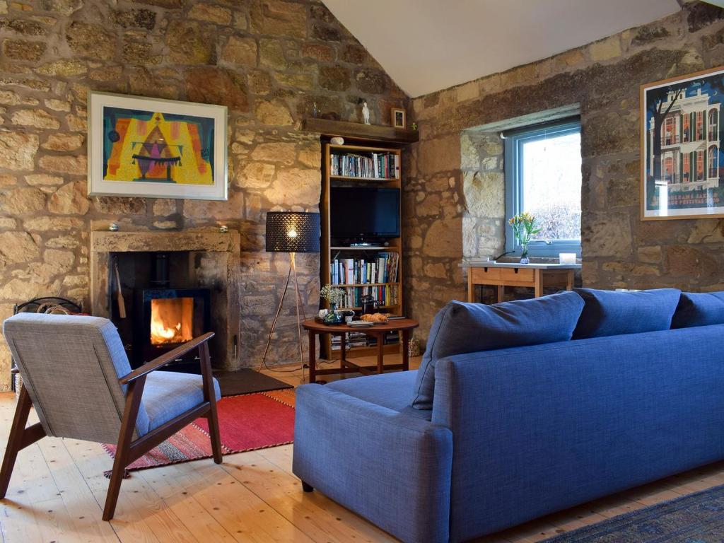 a living room with a blue couch and a fireplace at The Outside Room in Ladybank