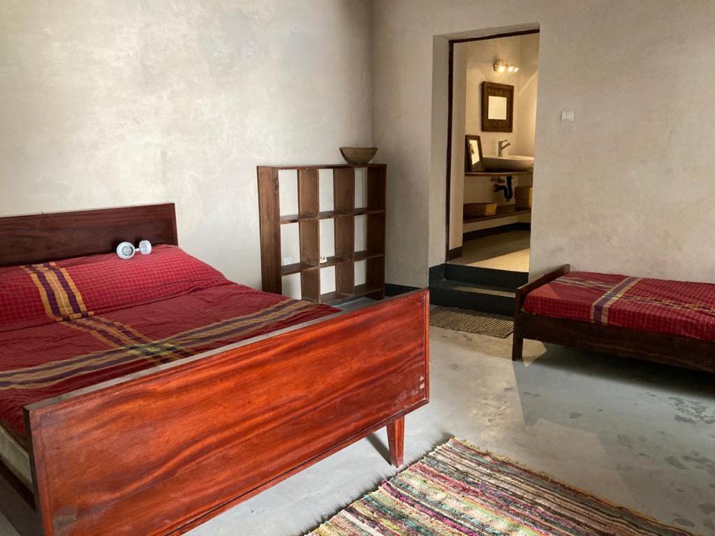 a bedroom with a wooden bed with a red comforter at Casa Fabula in Ilha de Moçambique