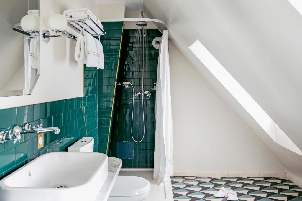 a bathroom with a toilet and a shower with green tiles at Grand Pigalle Hotel in Paris