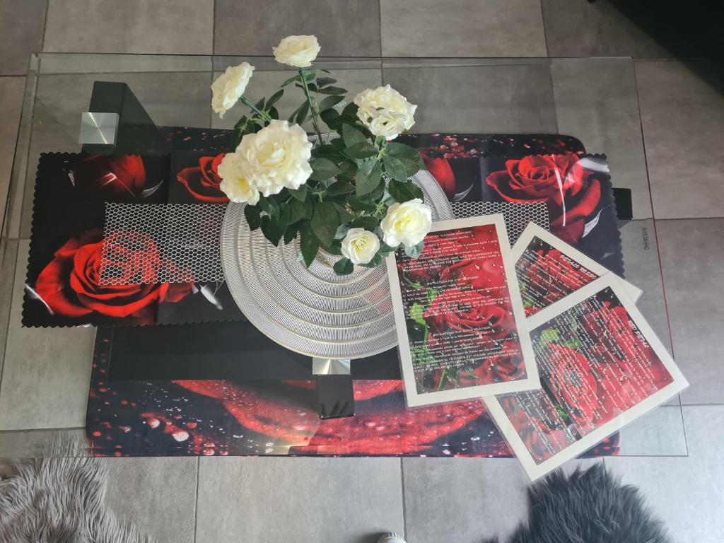 un jarrón con flores en una mesa con fotos en Petalo rosso, en Pegognaga