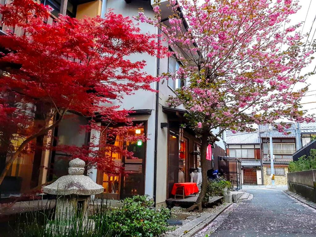 een straat met rode bomen voor een gebouw bij Guesthouse Soi in Kyoto