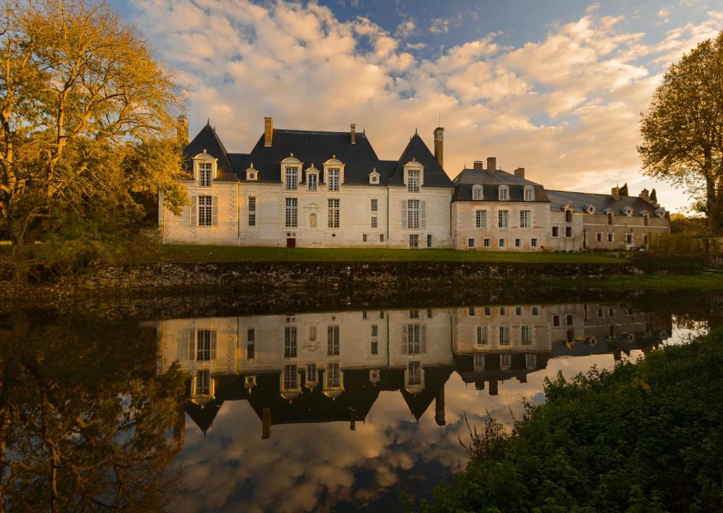 une grande maison avec sa réflexion dans l'eau dans l'établissement Chateau des Grotteaux Près Chambord, à Chambord