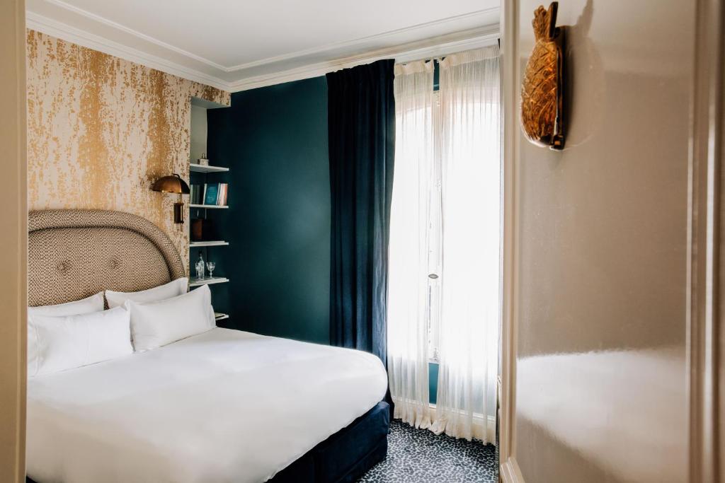 a bedroom with a white bed and a window at Grand Pigalle Hotel in Paris