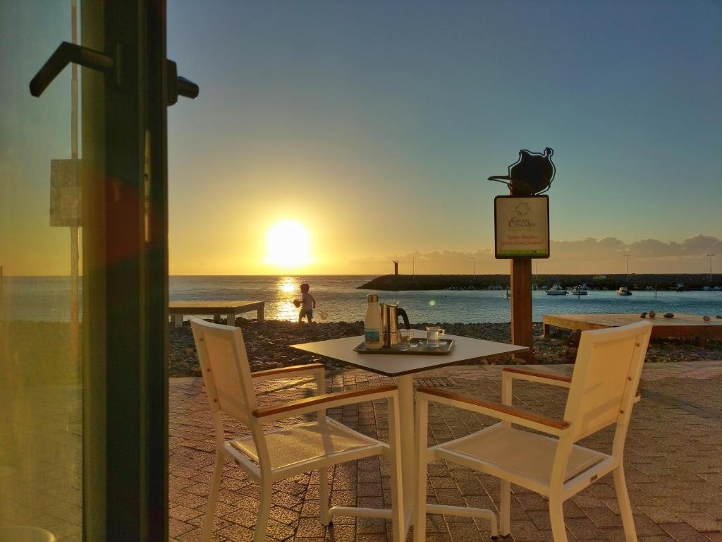 uma mesa e cadeiras na praia com o pôr do sol em De Sebastian 1 - estudio frente al mar em San Nicolás