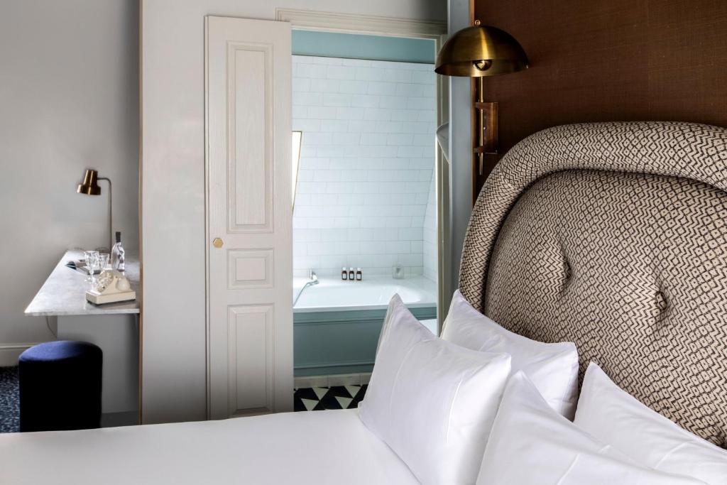 a bedroom with a bed and a bathroom with a tub at Grand Pigalle Hotel in Paris