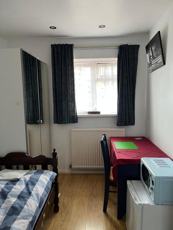 um quarto com uma cama, uma mesa e uma janela em Comfortable single bedroom with free on site parking em Kingston upon Thames