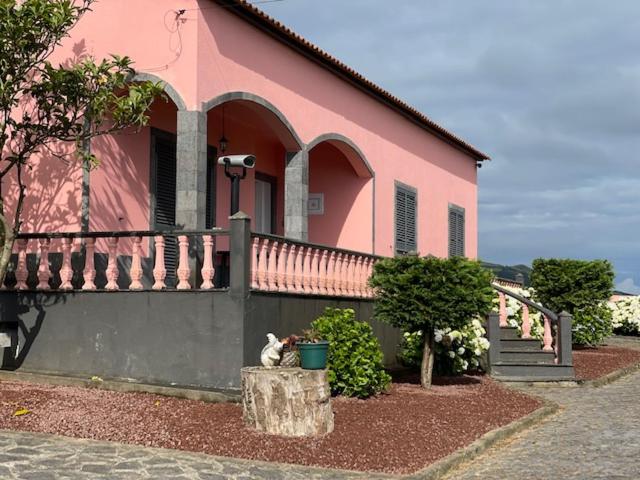 a pink house with a cat sitting in front of it at Quinta do Avô Dimas - Rural Home - São Brás in Porto Formoso