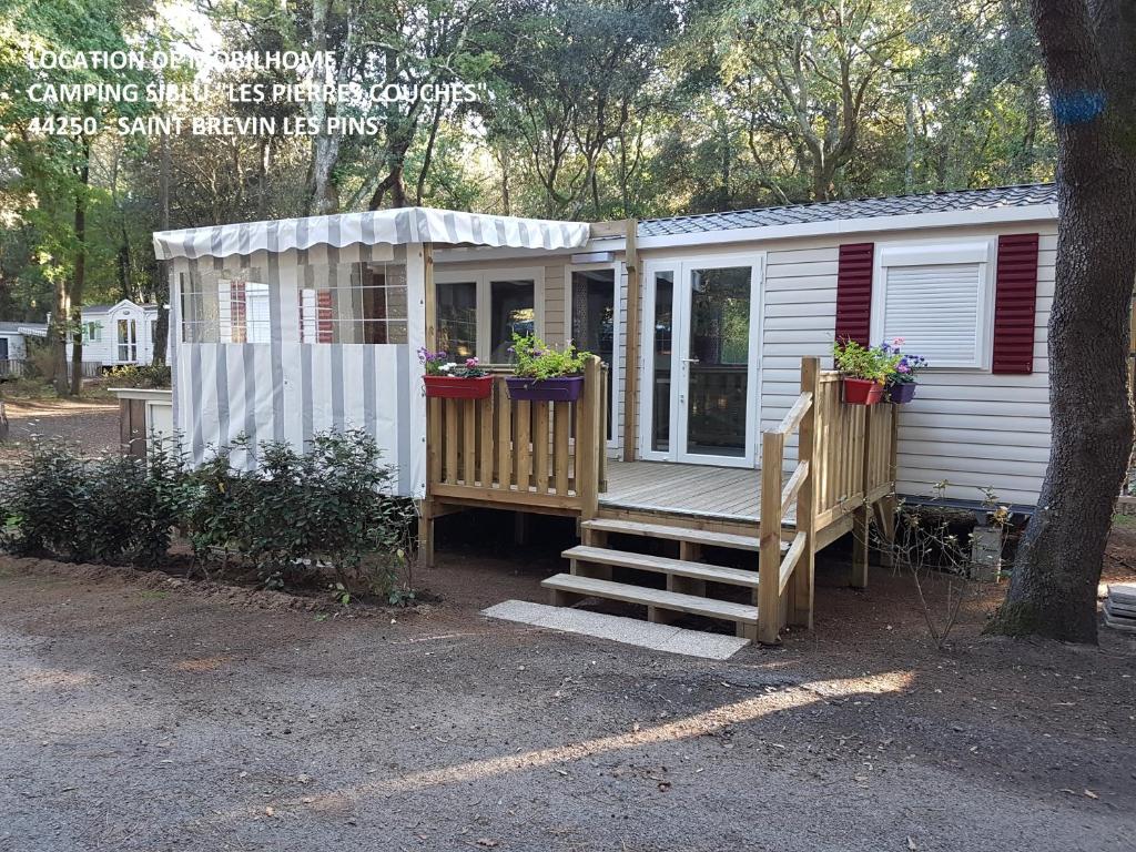 a tiny house with potted plants on the porch at Agréable Mobilhome 6 - 8 places in Saint-Brevin-les-Pins