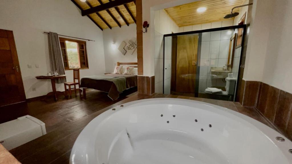a large bath tub in a room with a bedroom at Chalé Vila do Aeroporto in Monte Verde
