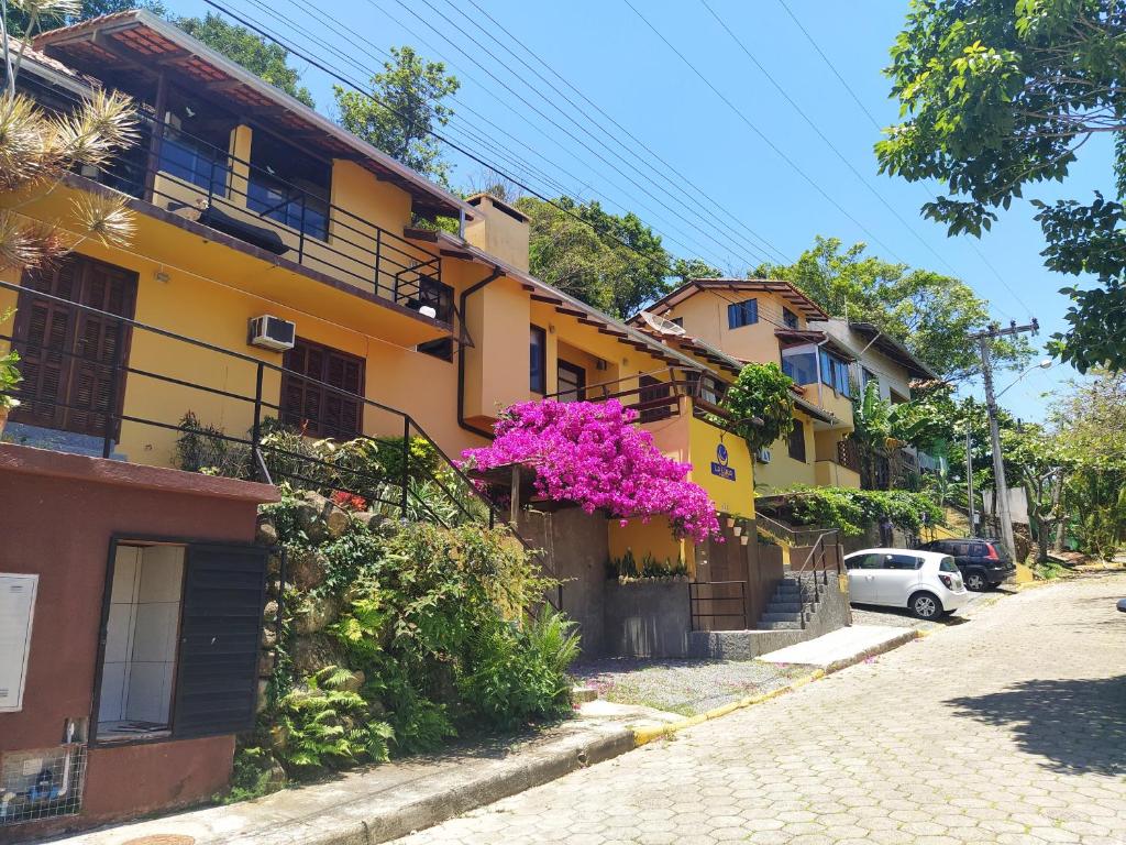 un edificio amarillo con flores púrpuras al lado de una calle en La Luna Studios, en Bombinhas