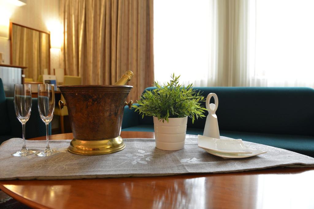 a table with two wine glasses and a plant on it at Hotel Karpos in Skopje