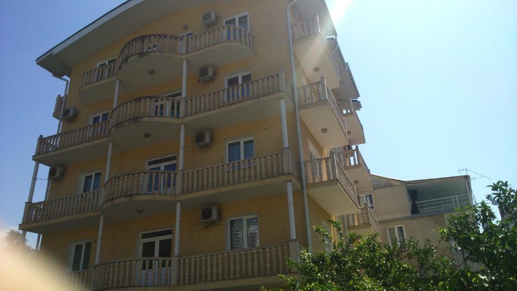 ein hohes gelbes Gebäude mit Balkonen darauf in der Unterkunft Margarita Guest House in Sochi