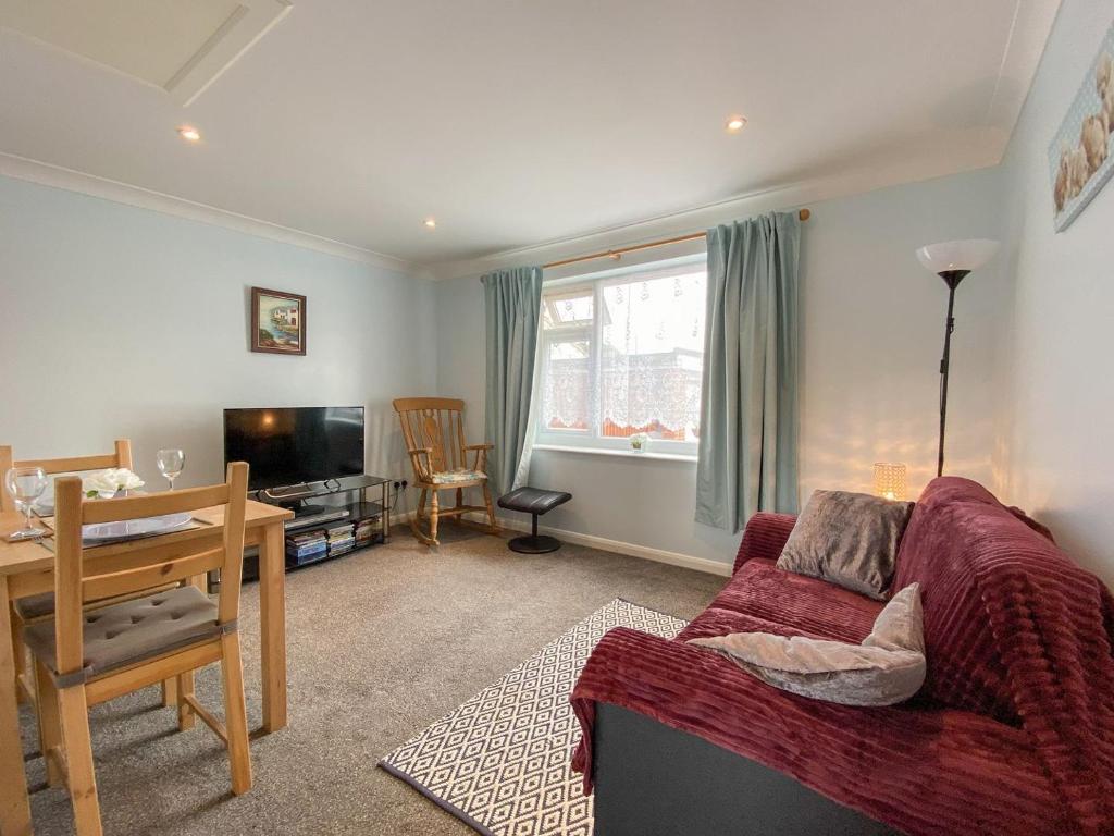 ein Wohnzimmer mit einem roten Sofa und einem Tisch in der Unterkunft The Annexe At Whitfield in Saint Margaretʼs at Cliffe