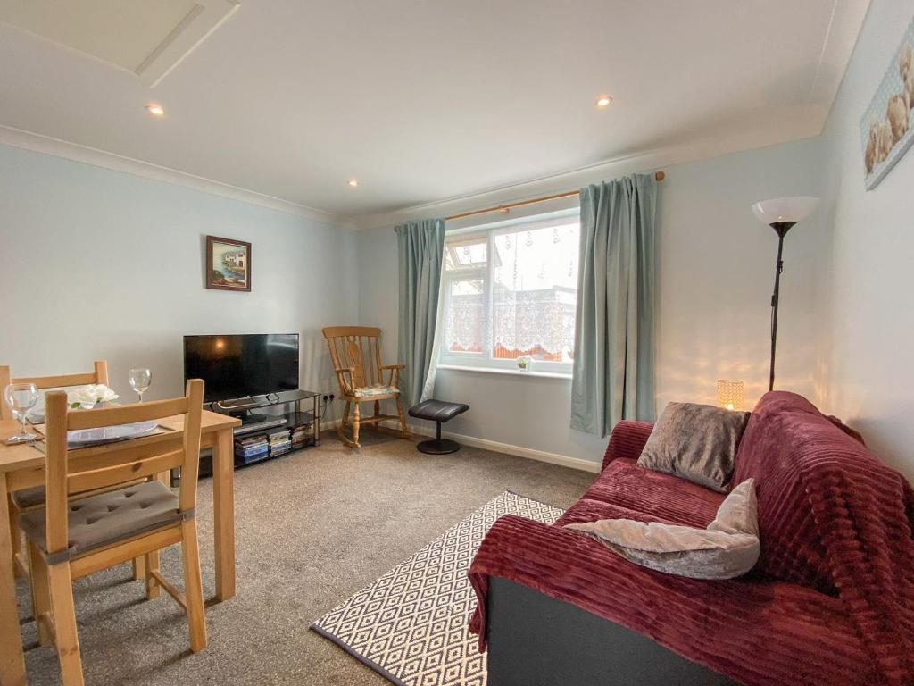 a living room with a red couch and a table at The Annexe At Whitfield in Saint Margaretʼs at Cliffe