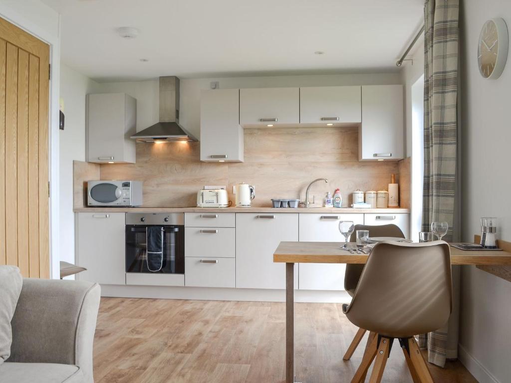 a kitchen with white cabinets and a wooden table at Rockworks Chalets No,3 - Uk7042 in Saint Marys