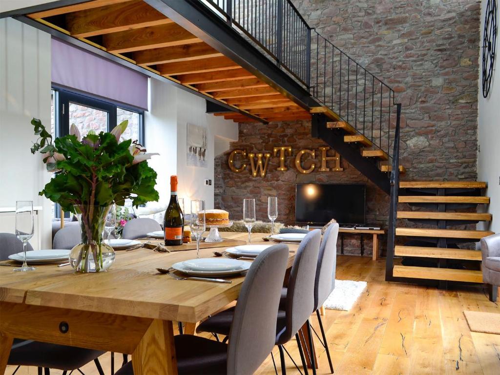 een eetkamer met een houten tafel en een trap bij Maes Merlin in Llanddeusant
