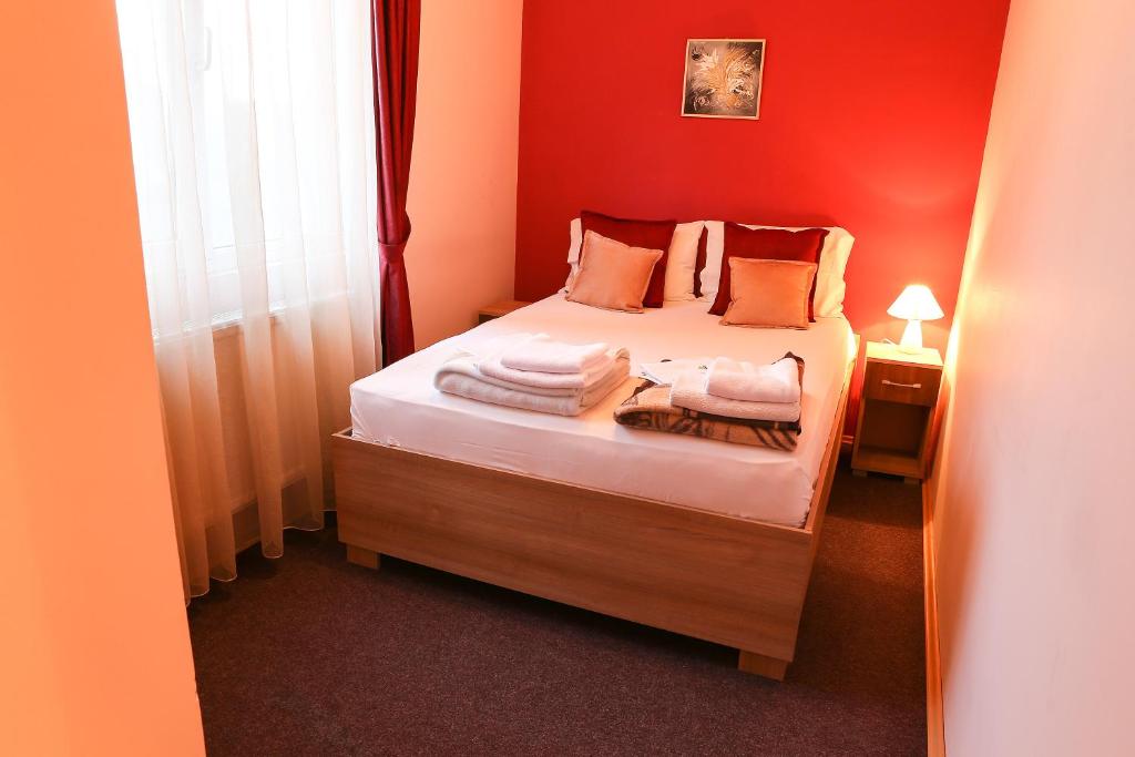 a small bedroom with a bed with red walls at Hotel North City in Mitrovicë