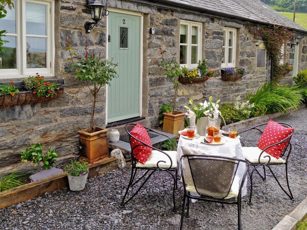 a table and chairs in front of a stone cottage at Bryn Ysgol in Yspytty-Ifan