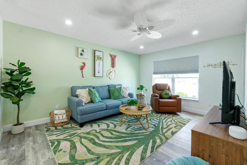 sala de estar con sofá azul y TV en Paradise Palms- Tropic Suite- Pool - Steps to Ocean - 10 min to Downtown en Saint Augustine