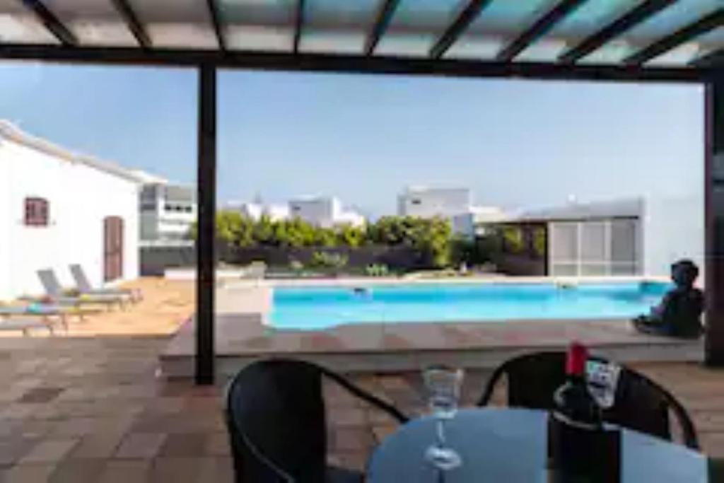 vistas a una piscina con mesa y sillas en Timanfaya Villa, en Tahiche