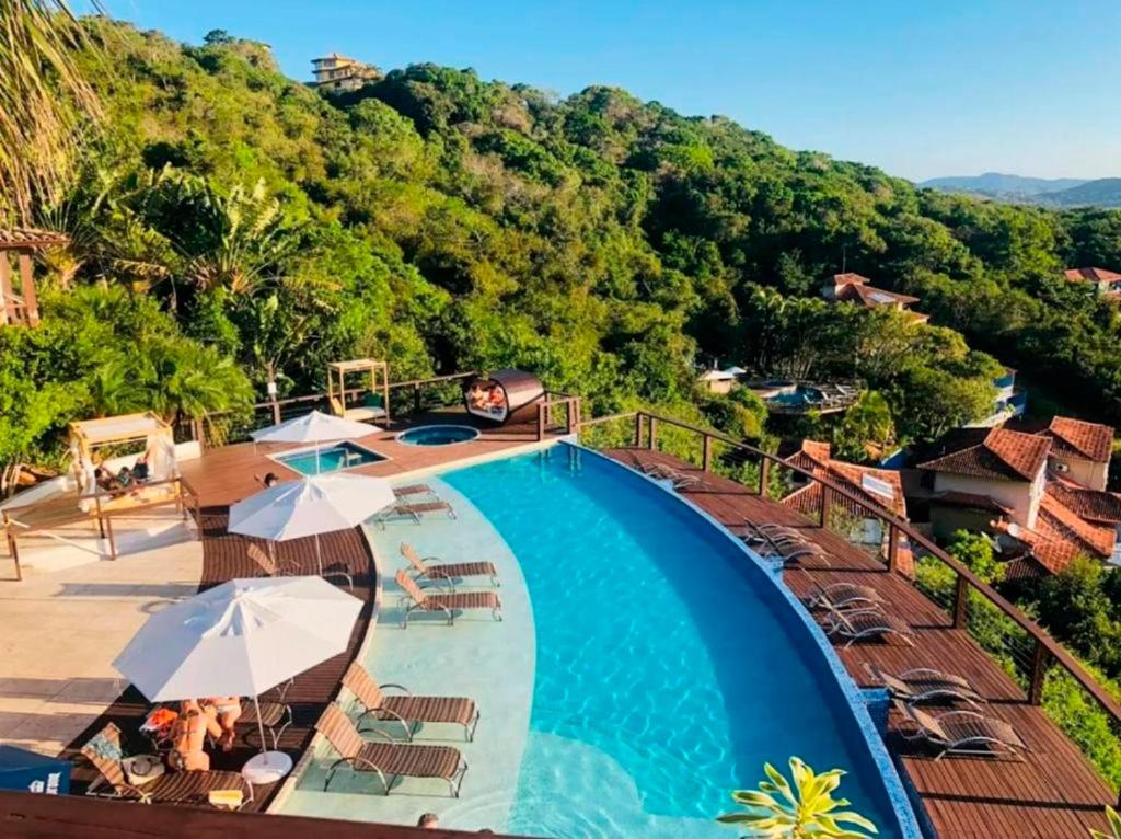 einen Pool mit Stühlen und Sonnenschirmen in einem Resort in der Unterkunft Eny Boutique Hotel & Spa in Búzios